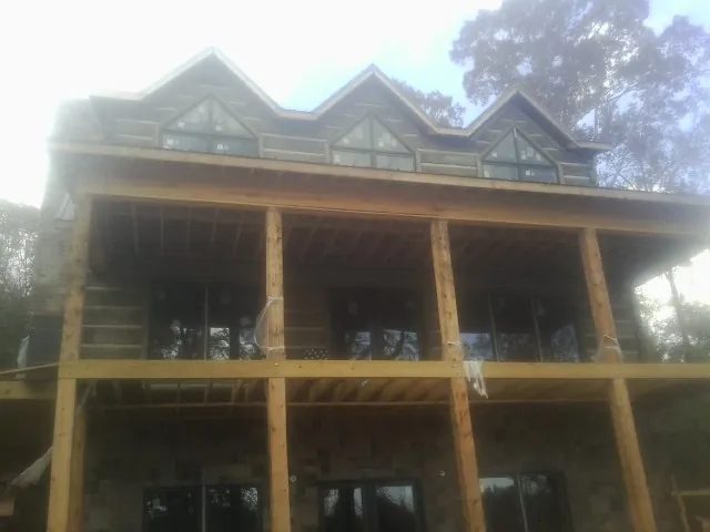 Dormers and porch framing on a large log home under construction — Roof Coating work by our crew in Summersville