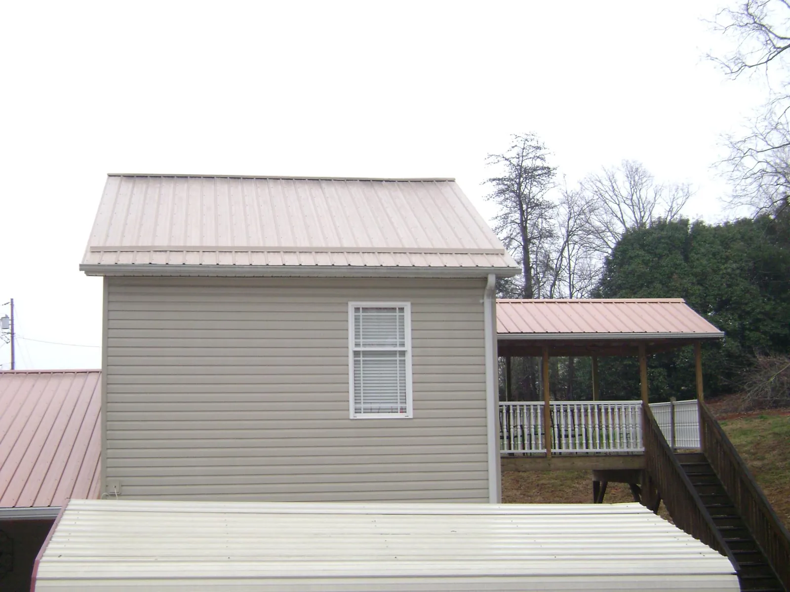 Tan metal roofs on a two story addition and attached porch, from a Roof Replacement job in Summersville