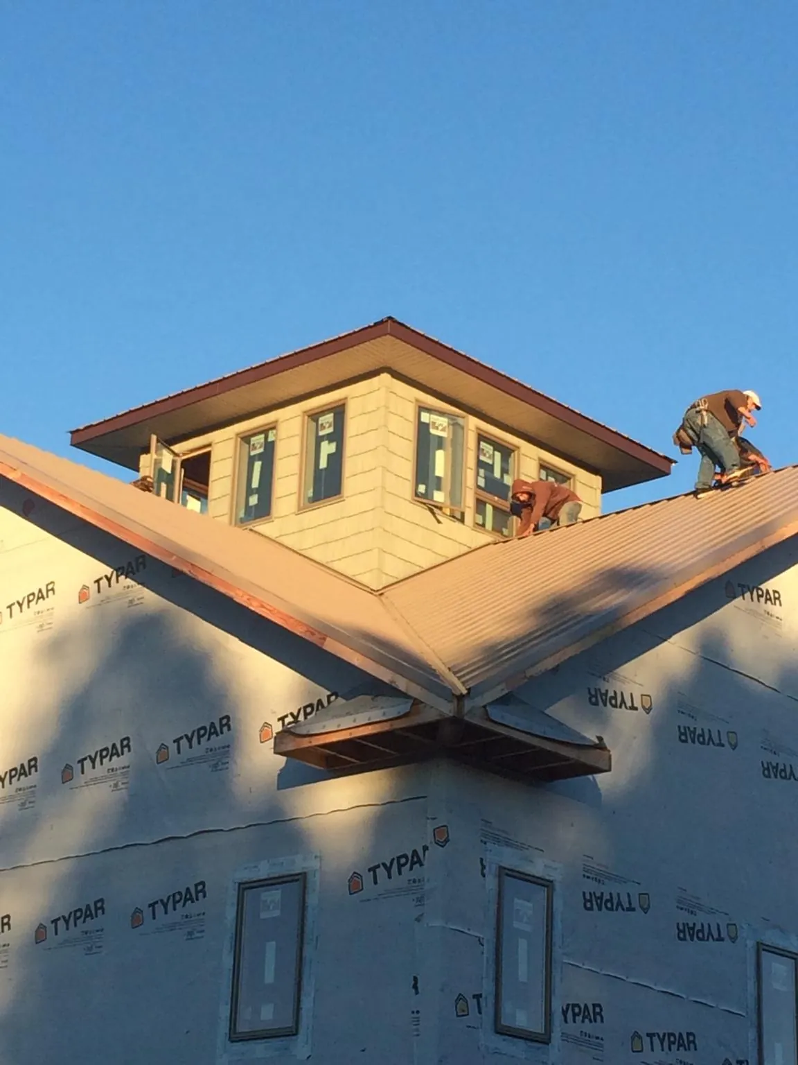 Roofers working around a rooftop cupola on a new metal roof at sunset — Roof Waterproofing in Summersville by Roofing Brothers